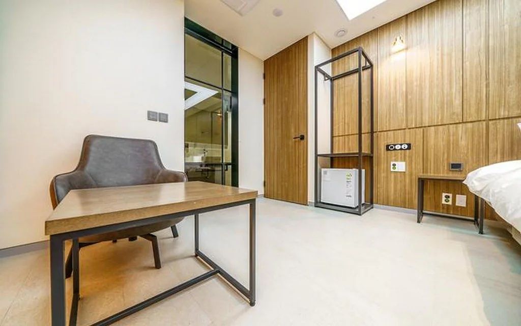 Una habitación de hotel moderna con un panel de madera en la pared, una cama, un escritorio y una silla.