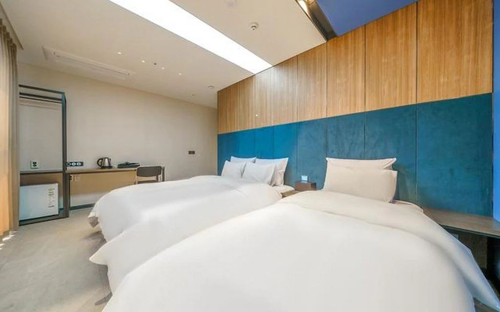 Habitación de hotel con dos camas, un escritorio y un espejo.