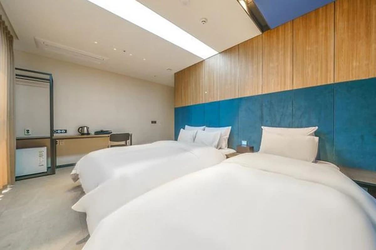 Habitación de hotel con dos camas, un escritorio y un espejo.