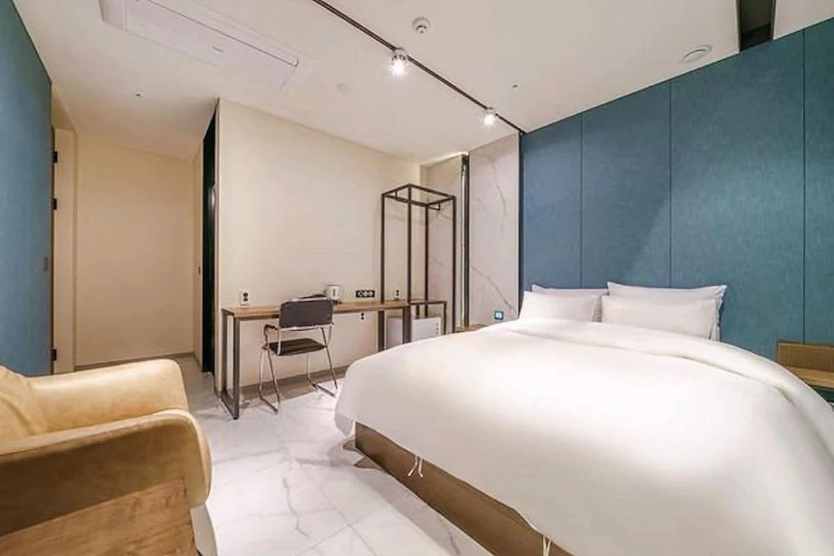 Habitación de hotel con cama, escritorio, silla y zona de ducha.