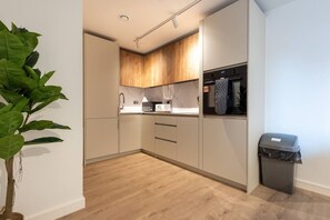 A modern kitchen with wooden cabinets, a microwave, and a trash bin. - Birmingham City Retreat No 66 (West Midlands)