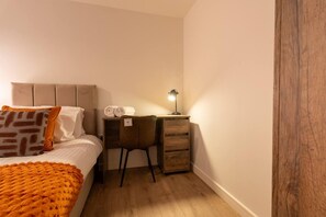 Un dormitorio con cama, escritorio y silla.