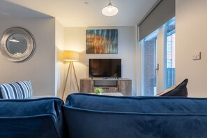 A modern living room with a sofa, a floor lamp, a flat-screen TV, and a painting on the wall. - Birmingham City Retreat No 66 (West Midlands)