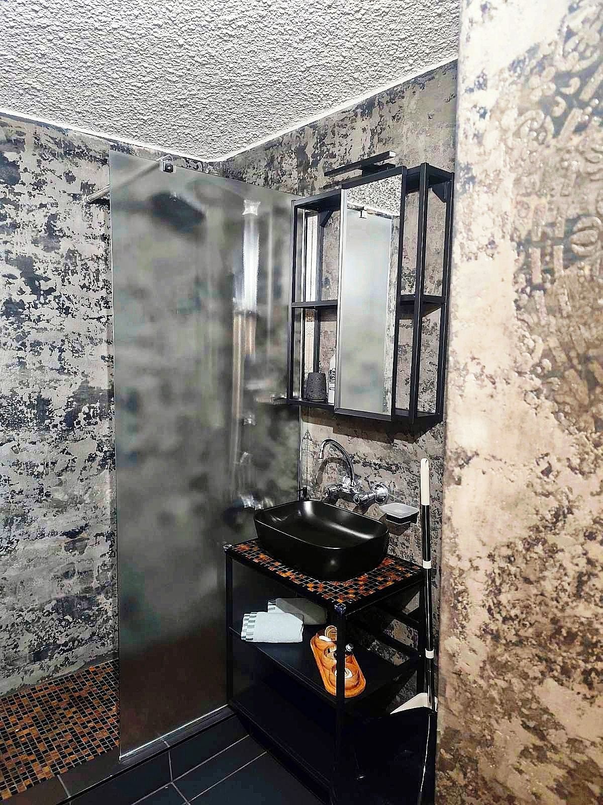 A bathroom with a black sink, a mirror, and a towel rack.