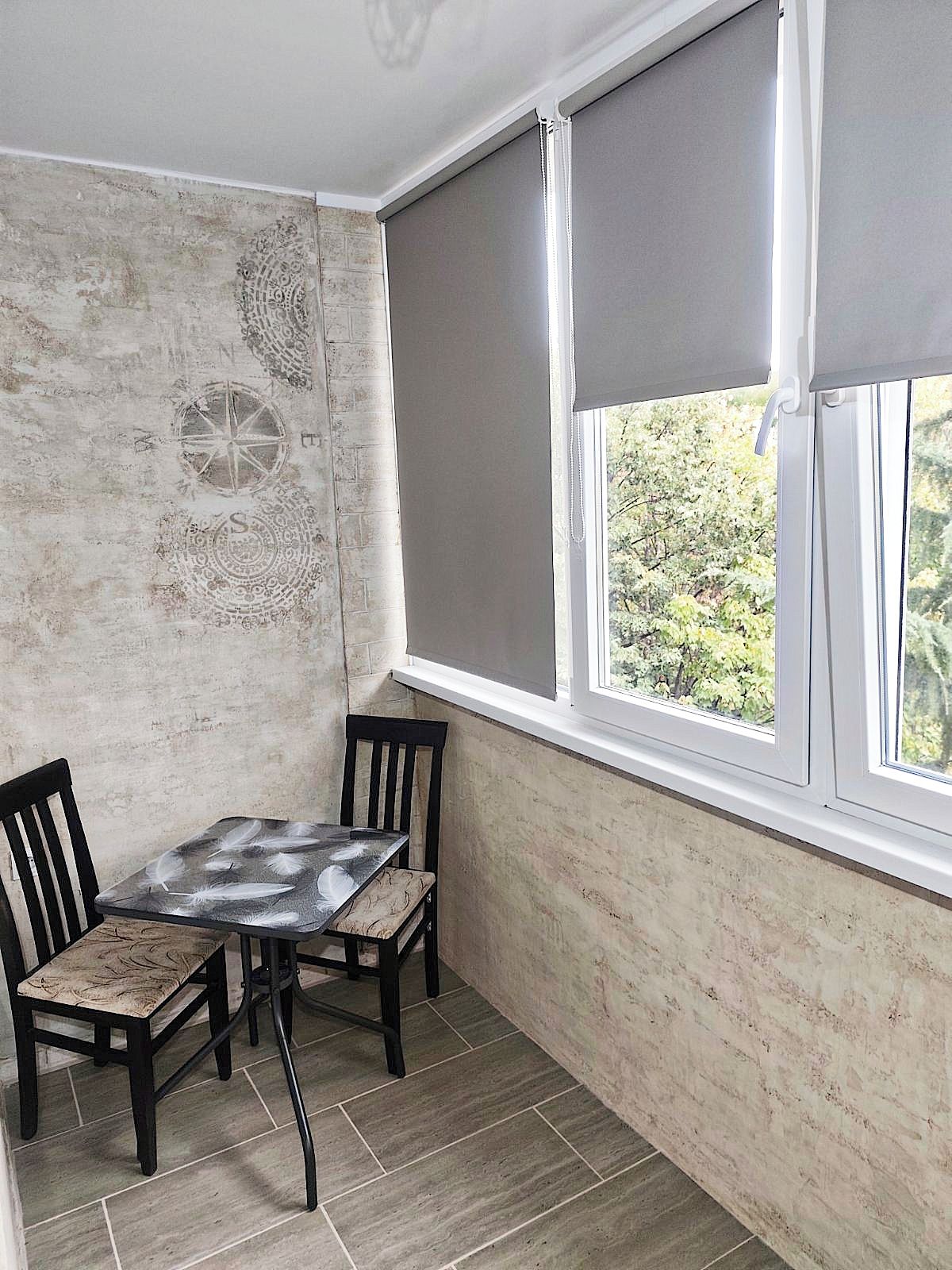 A corner room with a table and chairs, a window with blinds, and a textured wall.