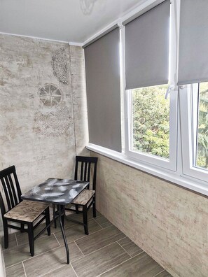 Una habitación de esquina con una mesa y sillas, una ventana con persianas y una pared con textura.