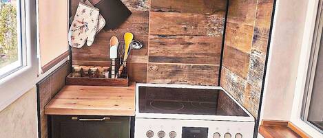 Une cuisine de taille réduite, équipée d’une cuisinière, d’un four et d’un petit plan de travail.