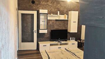 A modern living room with a flat-screen TV, built-in shelves, and a staircase leading to another level.