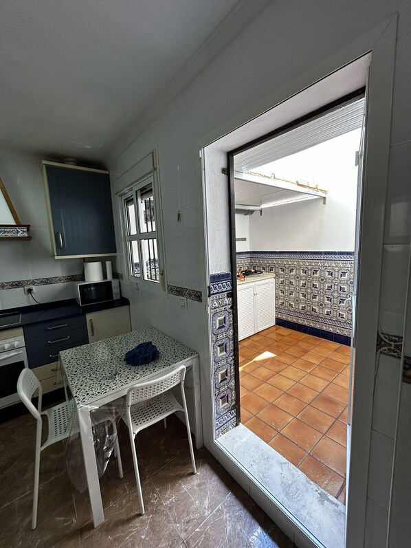 A compact kitchen with a dining area, a microwave, a sink, and a window with a view of the outside. - New Listing (Barbate)