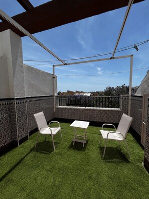 An outdoor seating area with artificial grass, two white chairs, and a small table. - New Listing (Barbate)