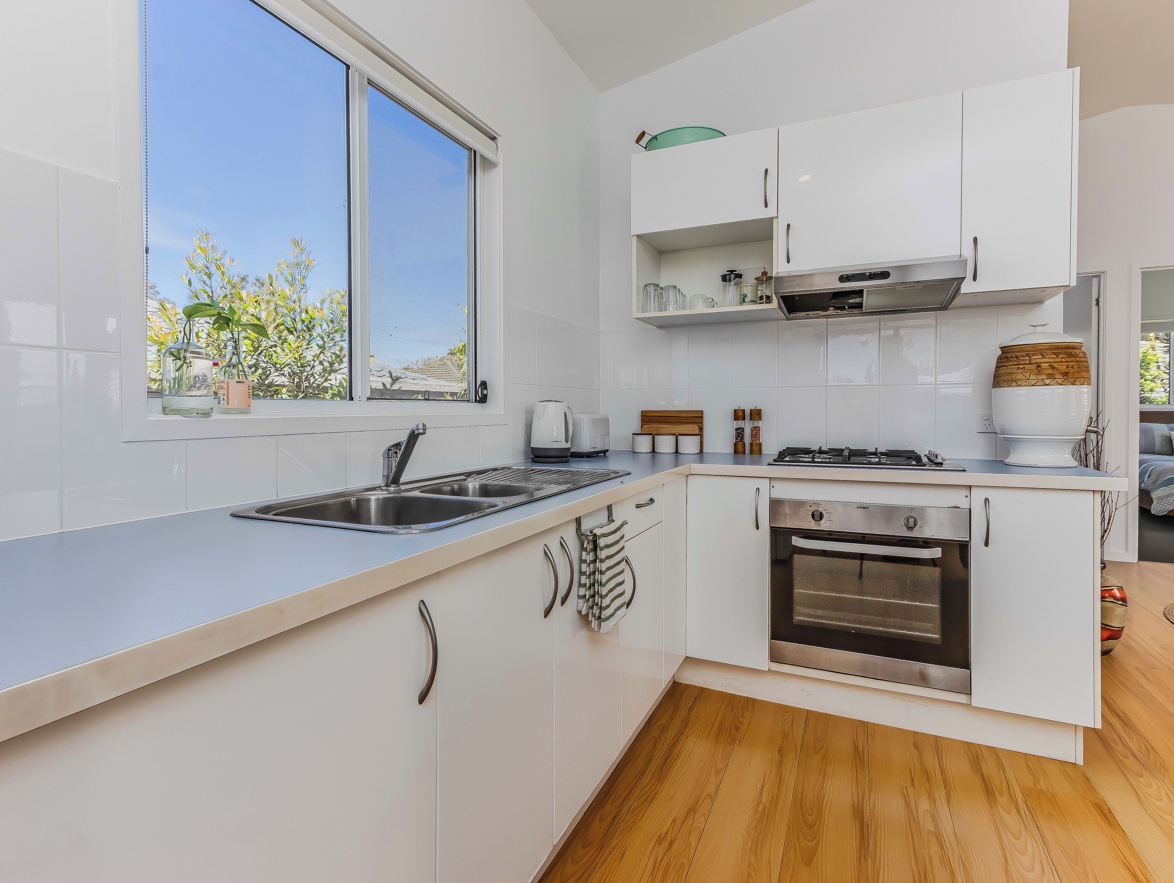 A modern kitchen with white cabinetry, a stainless steel sink, and a built-in oven.
