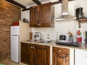 A kitchen with wooden cabinets, a white refrigerator, a double sink, and a coffee maker. - Villa Vida - Orebić (Orebic)