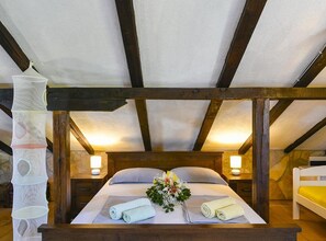 A bedroom with a wooden bed frame, two bedside lamps, a decorative wall hanging, and a small bedside table. - Villa Vida - Orebić (Orebic)