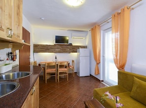 A compact kitchen with a dining area, a sofa, and a TV mounted above the counter. - Villa Vida - Orebić (Orebic)
