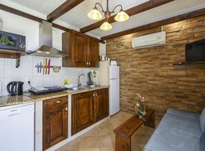 A compact kitchen with wooden cabinets, a built-in stove, and a stone wall. - Villa Vida - Orebić (Orebic)