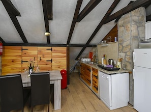 A compact kitchen with wooden cabinets, a built-in dishwasher, and a stone accent wall. - Villa Vida - Orebić (Orebic)