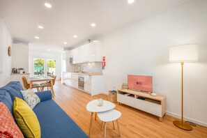 A modern living room with a sofa, a TV, and a dining area with a table and chairs. - GuestReady-Charming Retreat in Alcochete (Alcochete)