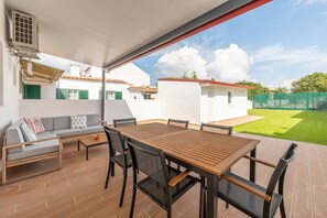 An outdoor patio with a wooden table and chairs, a sofa, and a ceiling fan. - GuestReady-Charming Retreat in Alcochete (Alcochete)