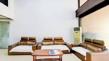 Habitación de hotel con sofá, una mesita de madera y aire acondicionado portátil.