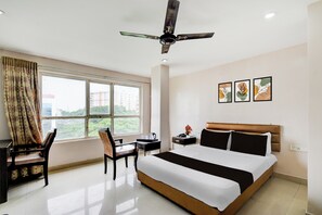 A hotel room with a bed, desk, chair, ceiling fan, window with curtains, and artwork on the wall. - Townhouse Narayanaguda Metro Station (Hyderabad)