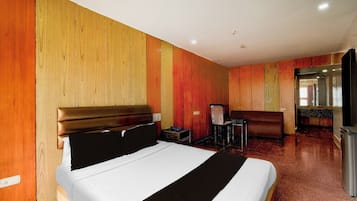 Una habitación de hotel con cama, escritorio, silla y espejo.