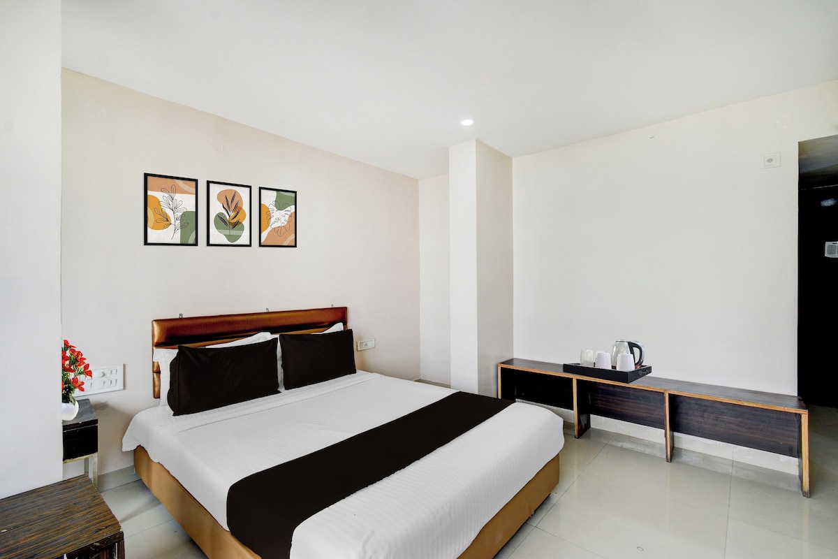 A hotel room with a bed, bedside tables, a nightstand, and artwork on the wall.