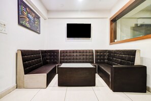 Un salon moderne avec un canapé d’angle, un téléviseur à écran plat et une fenêtre.