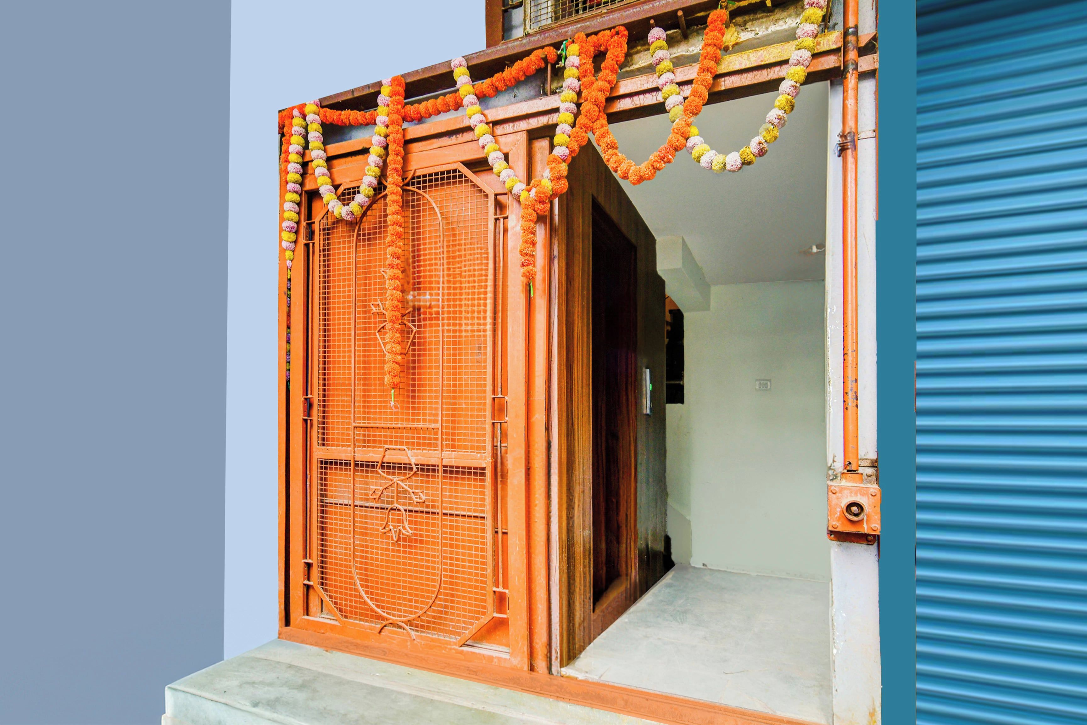 A doorway with a metal gate, a staircase leading up, and a blue shutter door.
