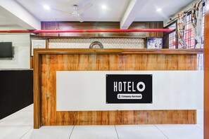 Un comptoir d’accueil d’hôtel avec un revêtement en bois, une horloge et un panneau indiquant qu’il s’agit d’un hôtel géré par une entreprise.