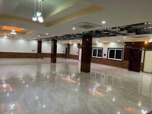 A spacious indoor area with a polished floor, wooden paneling, and a series of windows along one wall.
