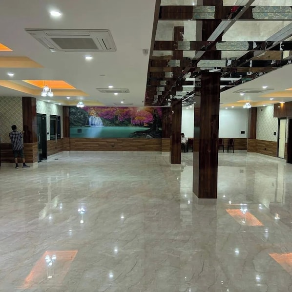 A spacious lobby with a marble floor, a mural of a waterfall, and a wooden staircase. - DREAMLAND PALACE (Siliguri)