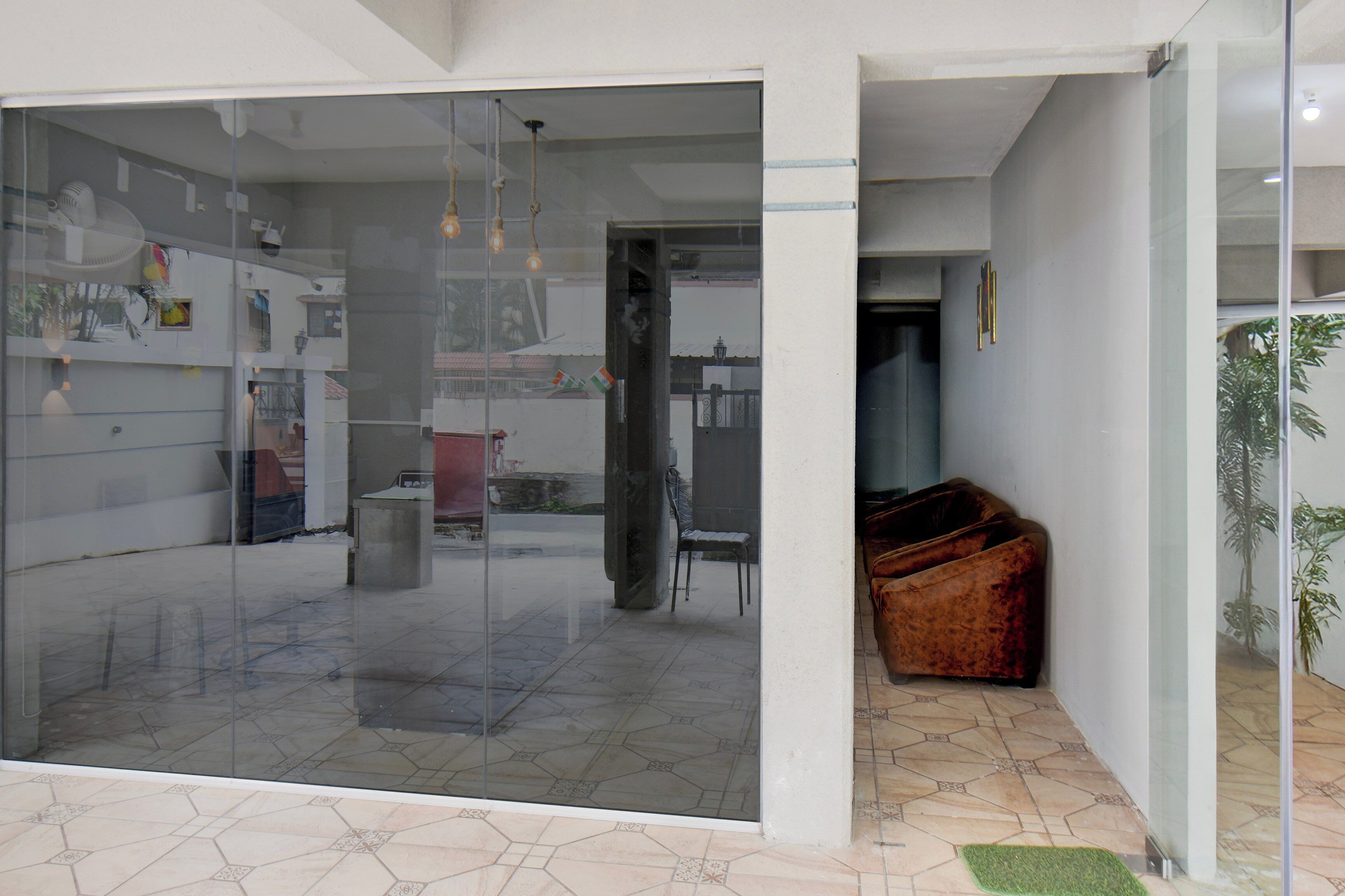 Ein modernes Interieur mit einer Glastrennwand, einer Sitzecke mit einem braunen Sofa und einem gefliesten Boden.