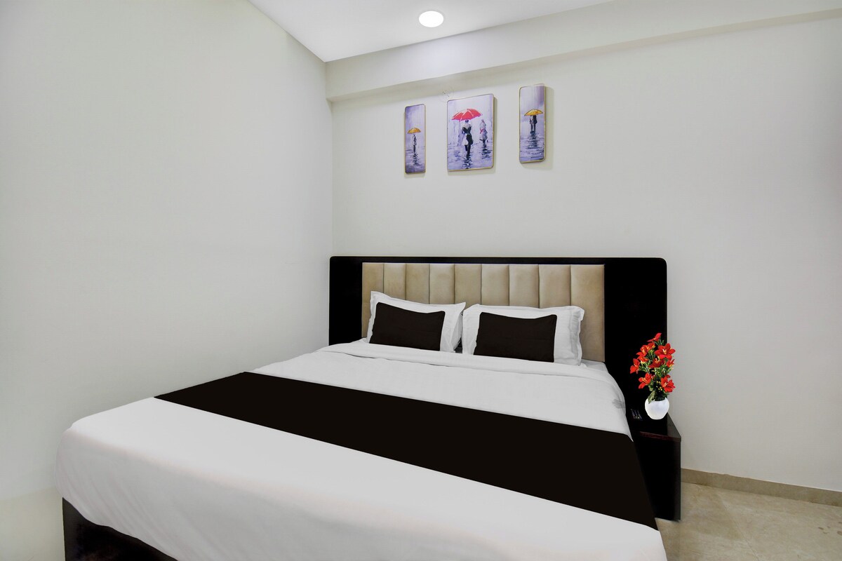 A hotel room with a bed, a nightstand, and a wall-mounted artwork.