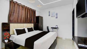 A hotel room with a bed, a desk, a chair, a TV, and artwork on the wall.