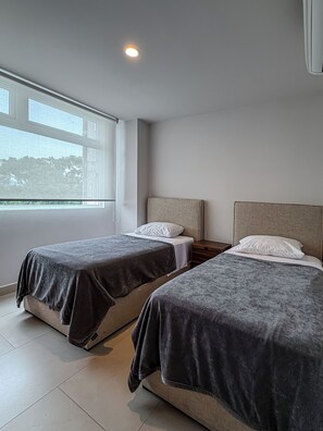 Ein Schlafzimmer mit zwei Betten, einem Fenster und einem Nachttisch.