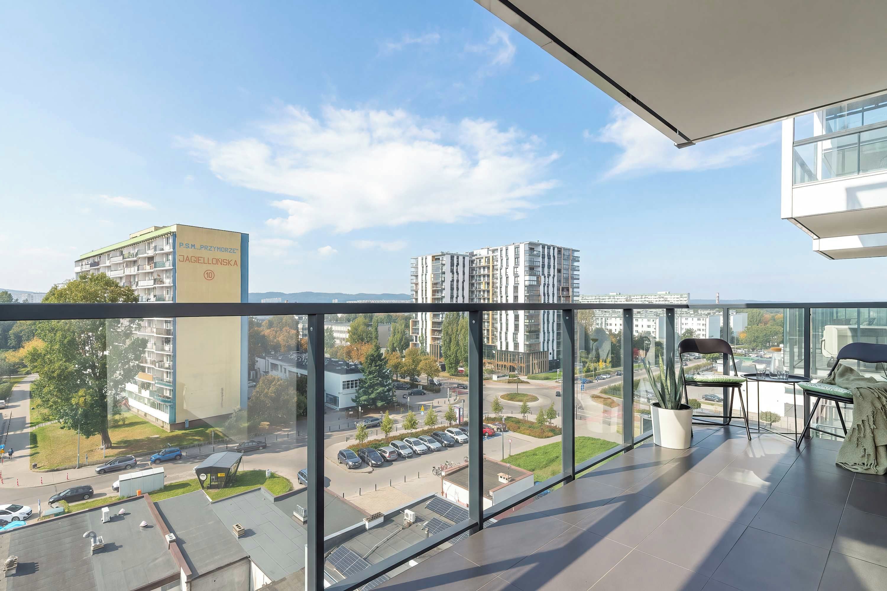 A modern apartment with a balcony, large windows, and a view of the cityscape.