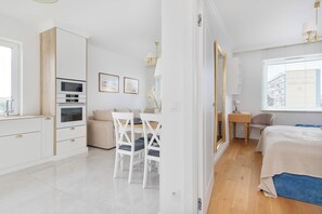 Quarto moderno e bem iluminado com cama, mesa de cabeceira e janela com persianas.