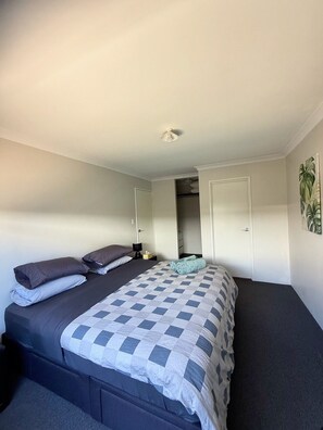 A bedroom with a bed, a nightstand, a door, and a wall-mounted light fixture. - comfortable 1 bedroom 1 bathroom unit attached to main house completely private. (Wellard)