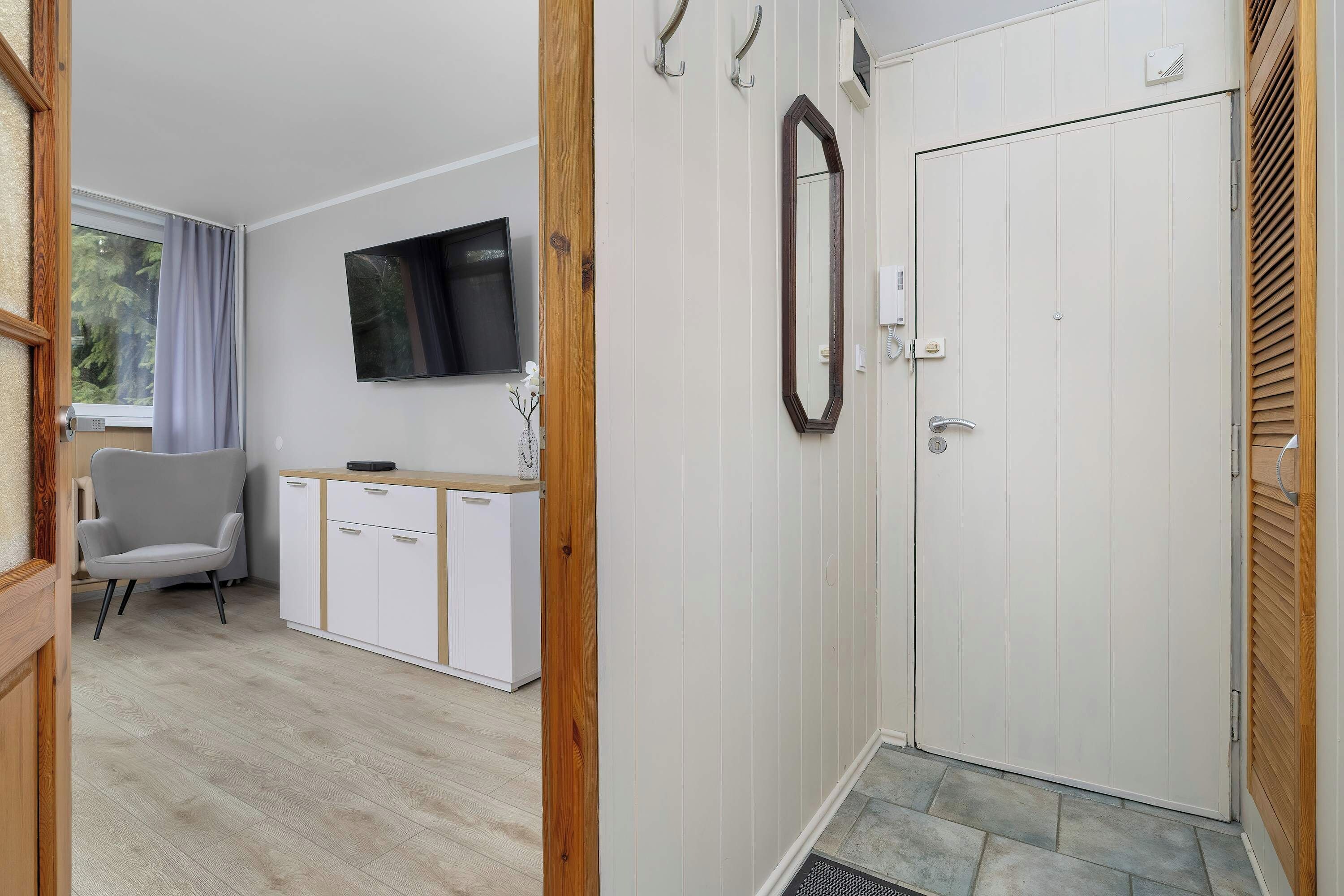 A hallway with a TV area, white doors, and wooden flooring.