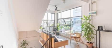 A modern interior with a staircase, wooden flooring, and large windows offering a view of the city.
