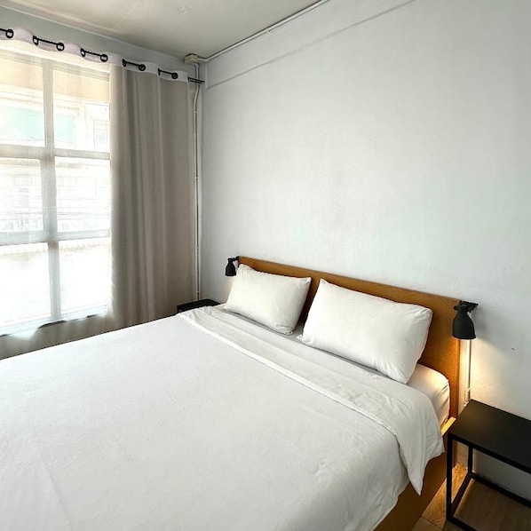 Una habitación de hotel con una cama grande, una mesita de noche y una ventana con cortinas.