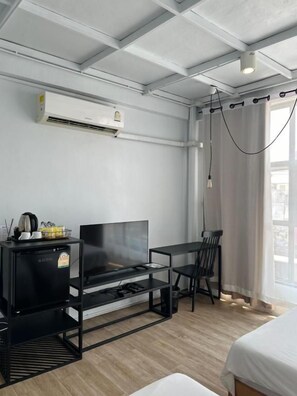 Habitación de hotel con televisión de pantalla plana, una mesita, una silla y una cama.