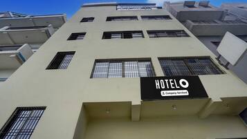 A hotel building with multiple windows and a sign indicating it is company-serviced.
