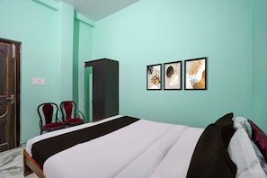 Quarto com cama, duas cadeiras, guarda-roupa e três obras de arte penduradas na parede.