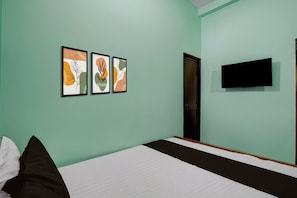 Un dormitorio con una cama, una puerta y tres obras de arte enmarcadas en la pared.