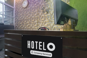 Balcão de recepção de hotel com aviso indicando serviço corporativo.