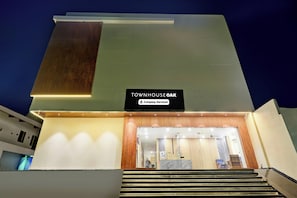 Ein modernes Gebäude mit einem Schild, auf dem 'TOWNHOUSE OAK' steht, und einem Hinweis auf einen serviceorientierten Betrieb.