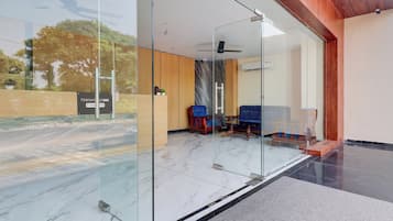 Zona de recepción con paredes de vidrio, mostrador de madera y disposición de asientos.