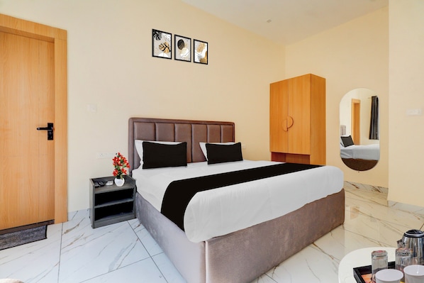 A hotel room with a bed, a nightstand, a mirror, and a wardrobe.