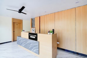 A reception desk with a marble top, wooden paneling on the walls, a ceiling fan, and a door labeled '101'.
